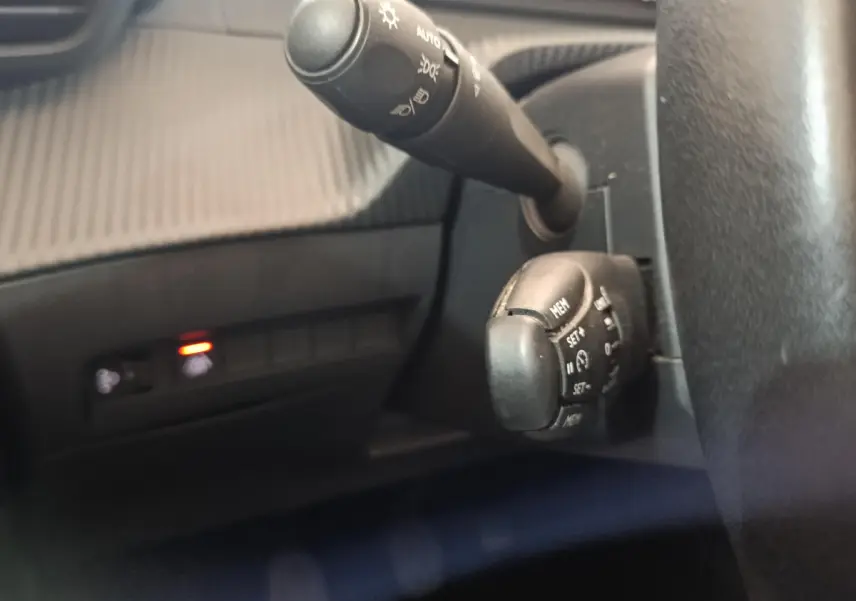 Gros plan sur les commandes au volant et la manette d'éclairage du tableau de bord d'une Peugeot 208 blanche de 2020.
