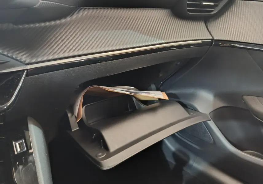 Gros plan sur la boîte à gants ouverte côté passager du Peugeot 208 blanc, soulignant la finition intérieure moderne.