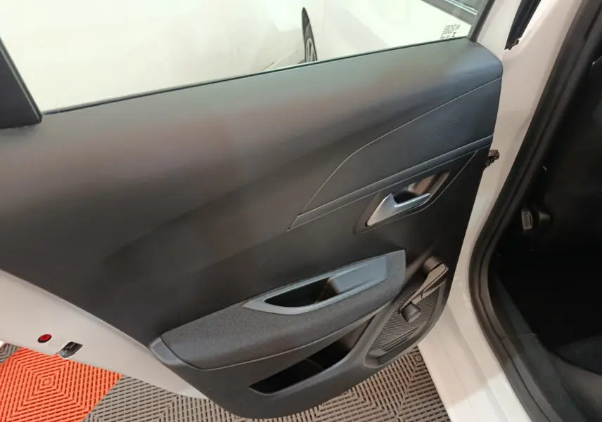 Vue rapprochée de la porte arrière droite noire intérieure d'une Peugeot 208 blanche, avec poignée et manivelle de vitre.