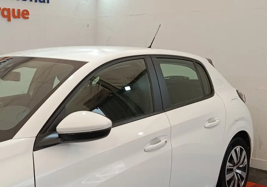 Vue latérale côté gauche d'une Peugeot 208 blanche PureTech 100 S&S Active Business, avec rétroviseur blanc et jantes stylisées.