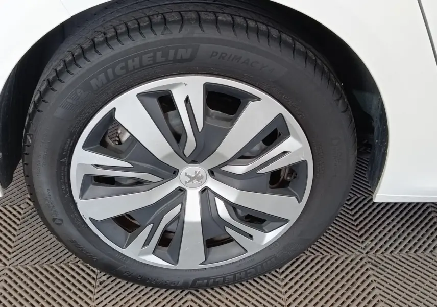 Gros plan sur la roue avant gauche blanche d'une Peugeot 208 PureTech 100 S&S Active Business avec jante stylisée.