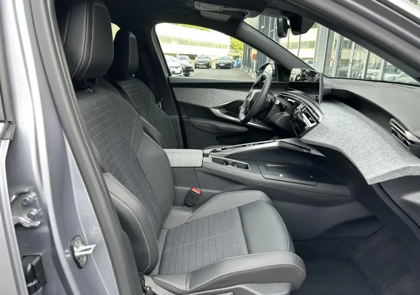 Vue intérieure côté conducteur du Peugeot 3008 gris Artense 2024, mettant en valeur les sièges tissu et cuir et le tableau de bord moderne.