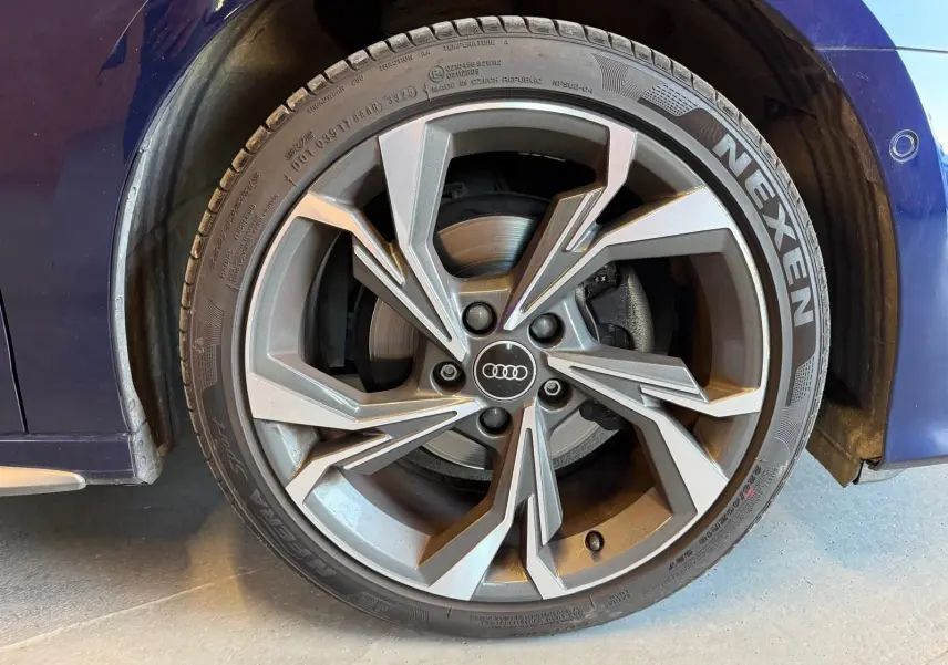Gros plan sur la roue avant droite d’une Audi A3 bleu 2022, jante alliage S-Line au design moderne et pneu Nexen.