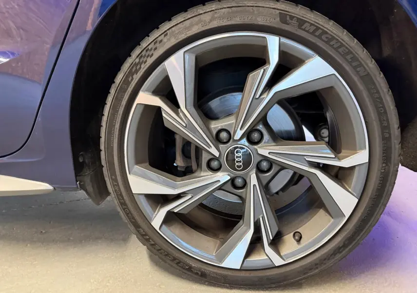 Gros plan sur la roue avant gauche d'une Audi A3 bleu 2022, mettant en valeur la jante alliage au design moderne.