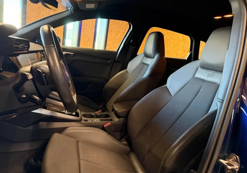 Vue intérieure côté conducteur de l'Audi A3 S-Line 2022 bleu, sièges sport en tissu noir avec logo S embossé.
