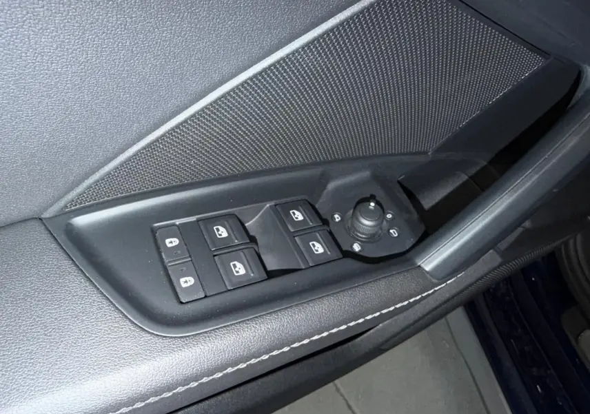Gros plan sur la commande des vitres et rétroviseurs côté conducteur de l'Audi A3 bleu 2022, finition S-Line.