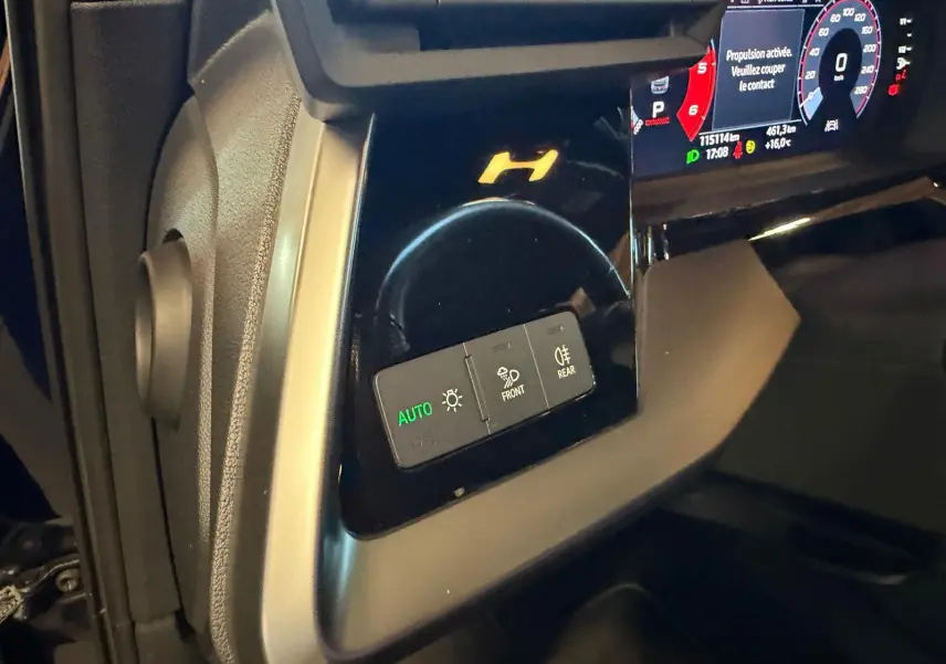 Détail du tableau de bord côté gauche d’une Audi A3 bleu 2022, avec commandes d’éclairage et affichage numérique.