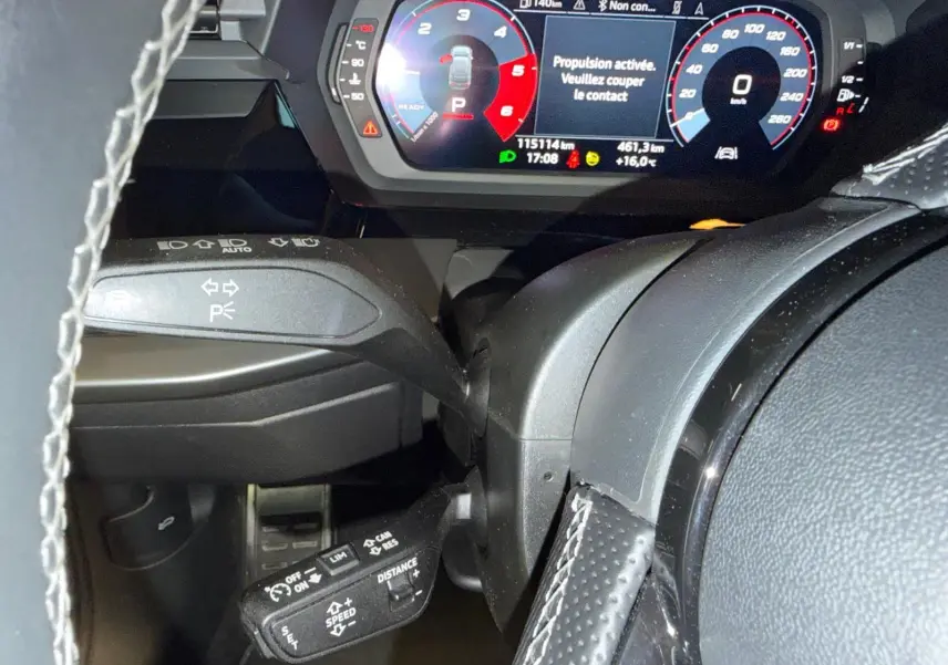 Vue rapprochée du tableau de bord et du volant noir perforé d’une Audi A3 2.0 TDI 150 S-TRONIC S-LINE avec affichage numérique coloré.