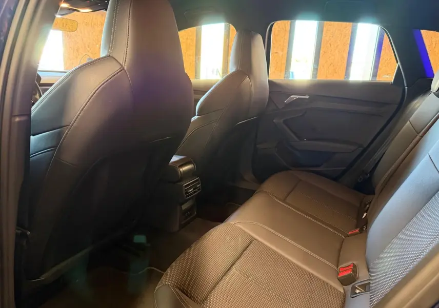 Vue intérieure arrière de l'Audi A3 2.0 TDI 150 S-Tronic S-Line 2022, sièges en tissu noir et habillage de porte sombre.