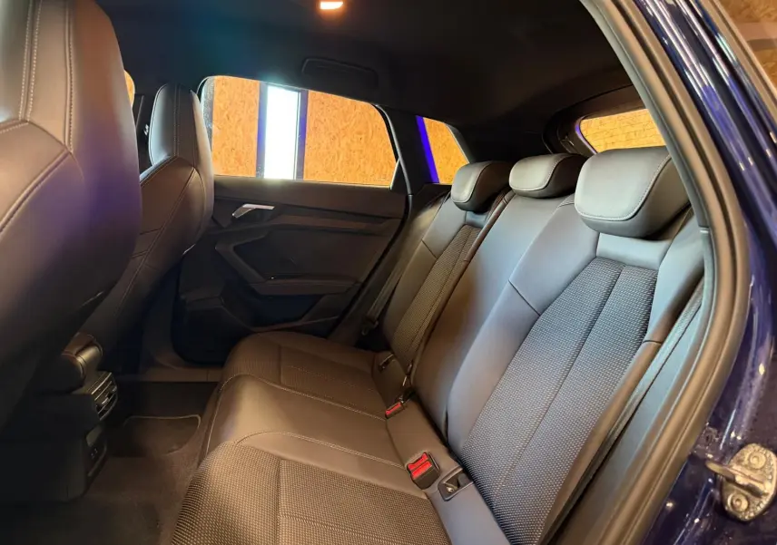 Vue intérieure côté droit des sièges arrière en tissu noir d'une Audi A3 2.0 TDI S-Line bleu 2022 avec porte ouverte.