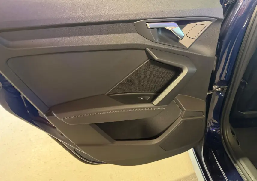 Vue rapprochée de la porte arrière droite bleu foncé d’une Audi A3 2.0 TDI 150 S-Line, avec garniture noire et poignée argentée.