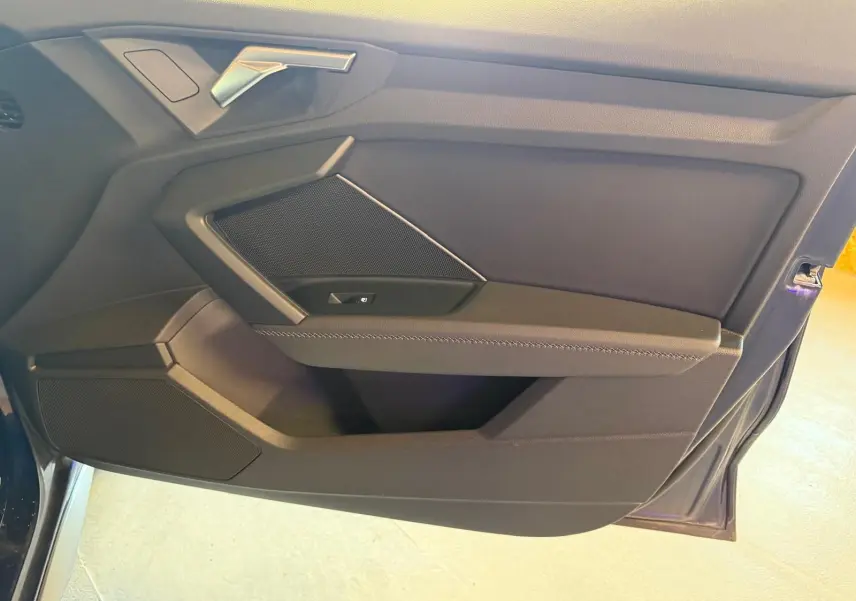 Vue rapprochée de la porte avant gauche de l’Audi A3 2.0 TDI 150 S-TRONIC S-LINE bleu, intérieur noir avec poignée argentée.