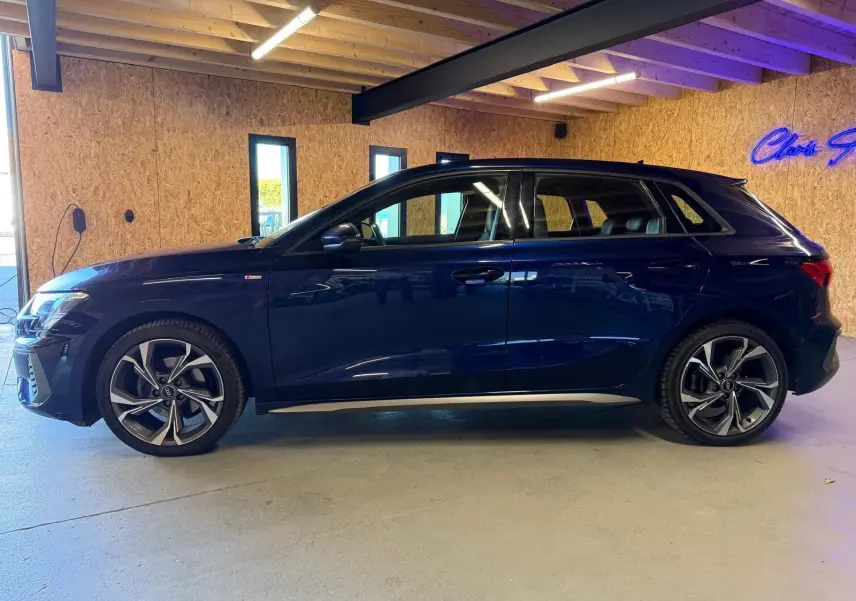 Audi A3 2.0 TDI S-Line bleu vue de profil côté gauche, avec jantes alliage distinctives en intérieur bois.