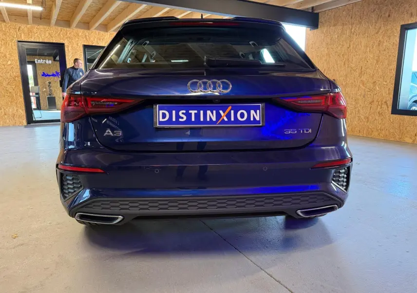 Vue arrière d'une Audi A3 bleu foncé 2022 avec logo et double sortie d'échappement intégrée au pare-chocs.