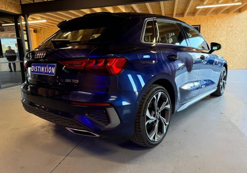Audi A3 2.0 TDI bleu vue 3/4 arrière droit, avec jantes alliage et feux arrière LED distinctifs.