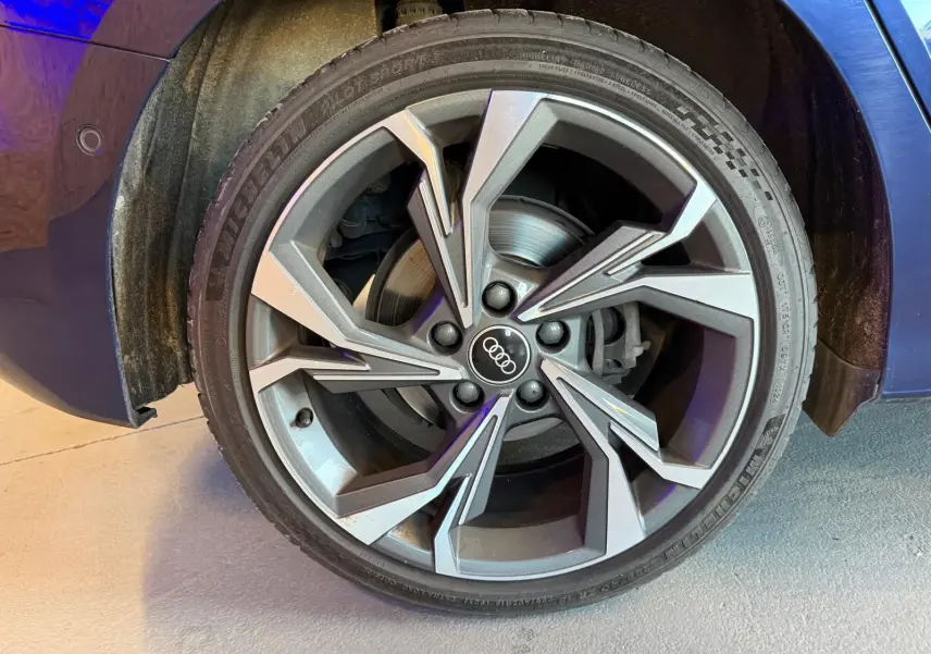 Gros plan sur la roue avant gauche d'une Audi A3 bleu 2022 avec jante alliage au design moderne.
