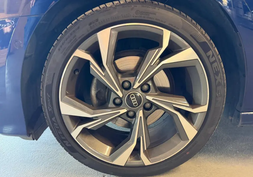 Gros plan sur la roue avant droite bleu foncé d’une Audi A3 2.0 TDI S-Line avec jante alliage à design géométrique.