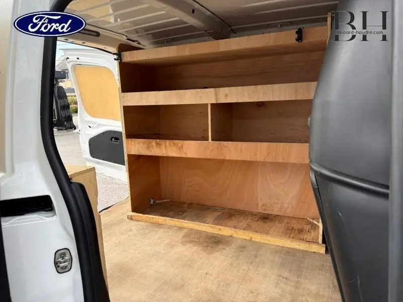 Vue intérieure arrière du Citroën Berlingo Fourgon blanc Banquise avec aménagements en bois pour rangement.
