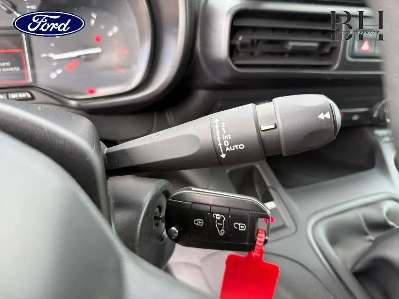 Gros plan sur la commande d’essuie-glace et clé insérée dans le contact d’un Citroën Berlingo Fourgon blanc, intérieur noir.