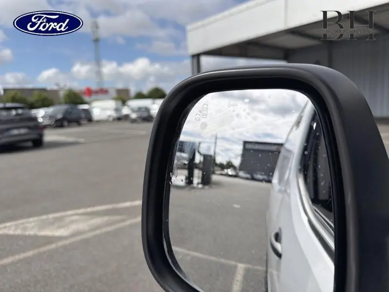 Rétroviseur côté droit d’un Citroën Berlingo Fourgon blanc Banquise, vue partielle avec reflet du parking.