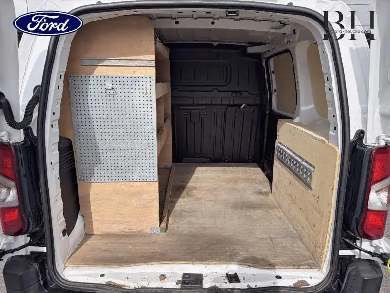 Vue arrière ouverte du Citroën Berlingo Fourgon blanc Banquise montrant l'aménagement intérieur en bois avec étagères.