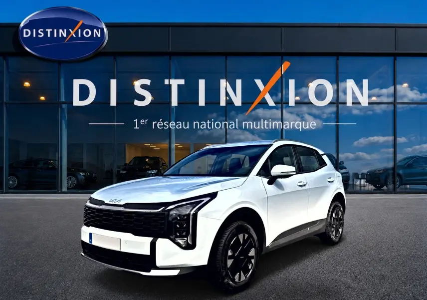 KIA Sportage 1.6 hybride blanc en 3/4 avant droit, avec calandre noire et jantes alu noires devant un showroom Distinxion.