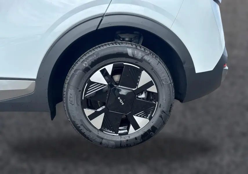 Gros plan sur la roue arrière droite du KIA Sportage blanc 2026 avec jante alu noire et argentée au design géométrique.