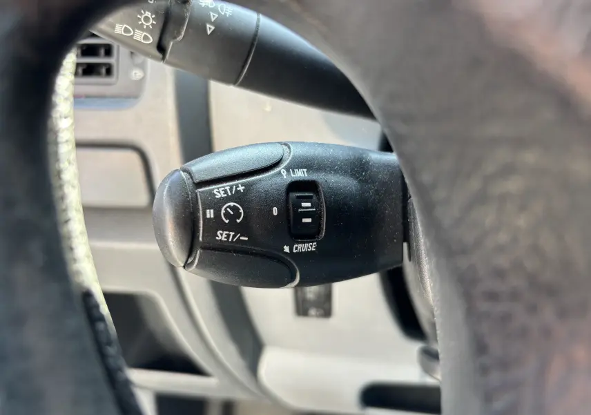 Gros plan sur la commande de régulateur de vitesse noire du FIAT Scudo Fourgon blanc, vue côté conducteur.