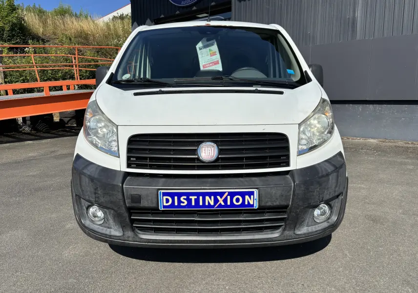 Vue frontale d'un fourgon FIAT Scudo blanc de 2010 avec pare-chocs noir et plaque Distinxion visible.