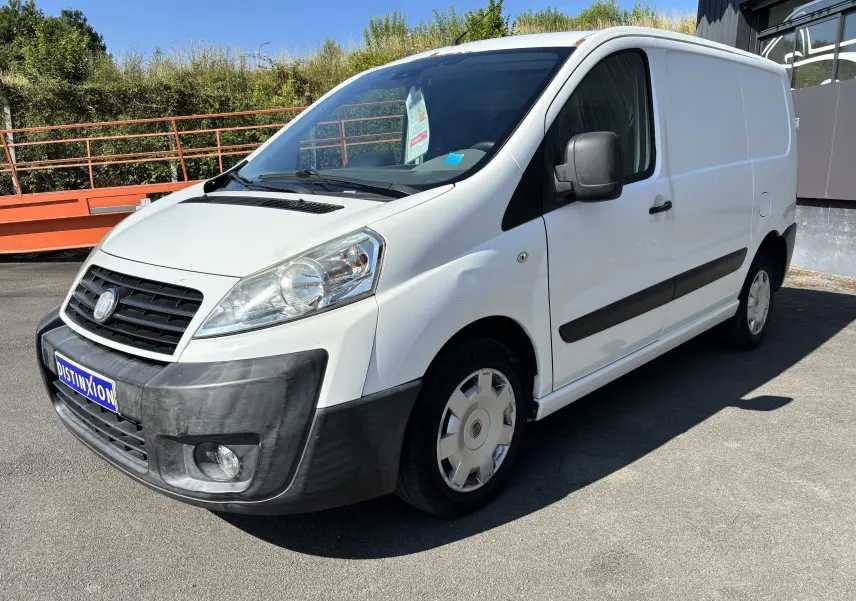 Fourgon blanc Fiat Scudo II 1.6 MJTD vu en 3/4 avant droit, avec pare-chocs noir et jantes d'origine.