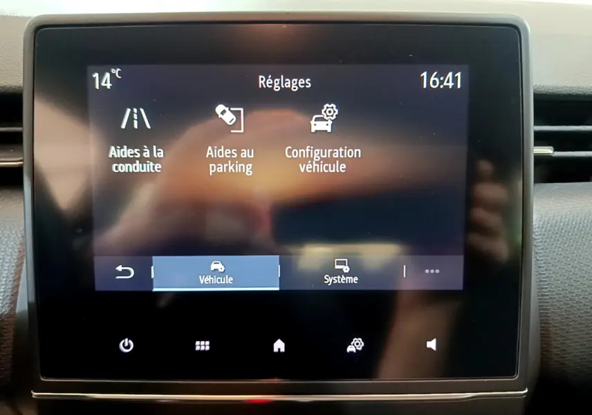 Écran tactile central de la Renault Clio Business blanc, affichant les réglages d'aides à la conduite et parking.