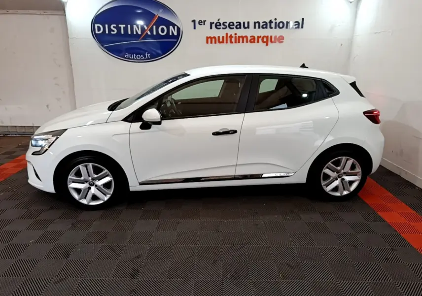 Profil droit d'une Renault Clio Business blanche 2021 avec jantes alliage et feux LED visibles en intérieur showroom.