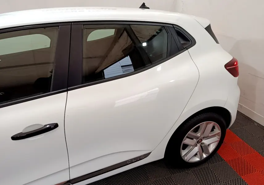 Vue latérale côté gauche d'une Renault Clio blanche avec poignées noires et jantes alliage visibles.