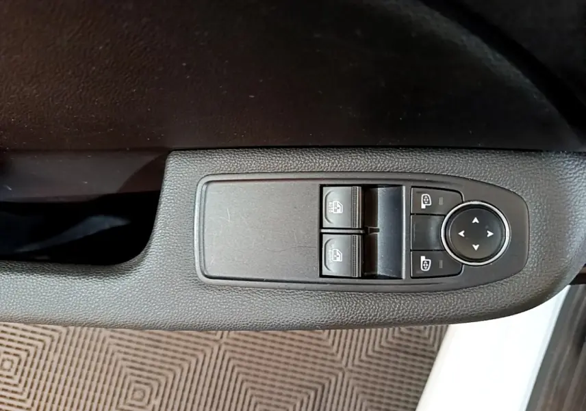 Gros plan sur les commandes de lève-vitres et réglages des rétroviseurs côté conducteur d'une Renault Clio blanche 2021.