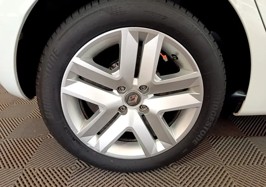 Gros plan sur la roue avant droite blanche d'une Renault Clio Business SCe 65 avec jante alliage et logo Renault central.