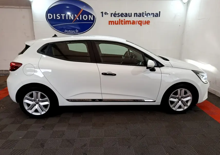 Profil droit d'une Renault Clio Business blanche 2021, avec jantes alliage et poignées noires, en intérieur showroom.