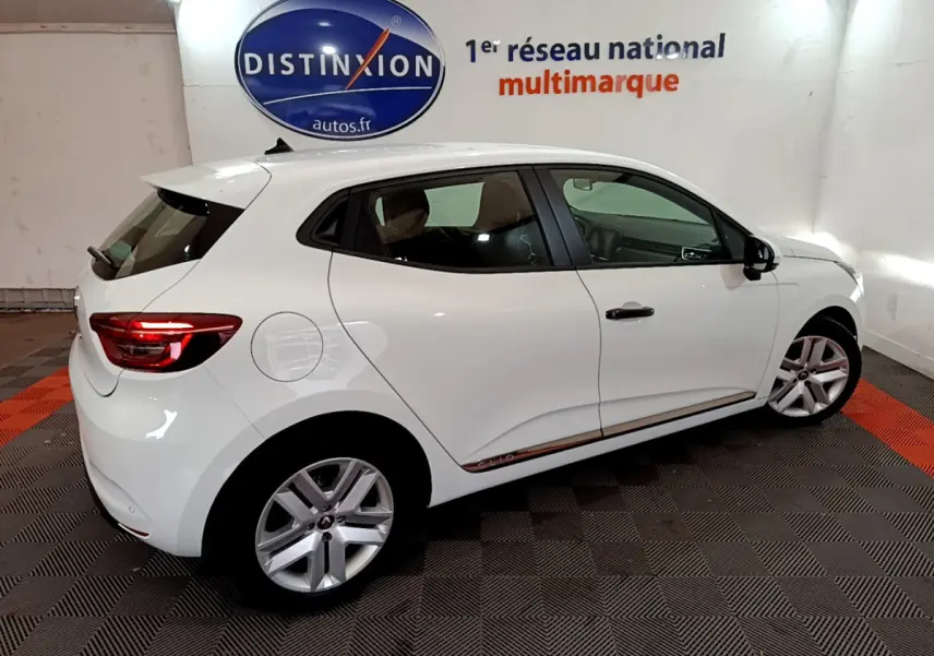 Renault Clio Business blanc vue 3/4 arrière côté droit, feux arrière allumés et jantes alliage visibles.