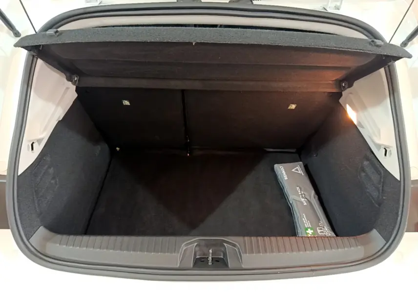 Coffre ouvert vu de dessus de la Renault Clio Business blanc, avec trousse de secours visible à droite.