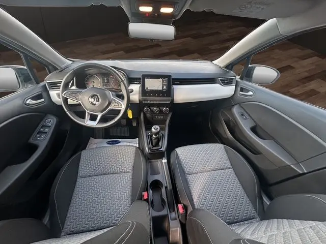 Vue intérieure avant de la Renault Clio V TCE 90 Evolution 2023, tableau de bord gris clair et sièges tissu gris noir.