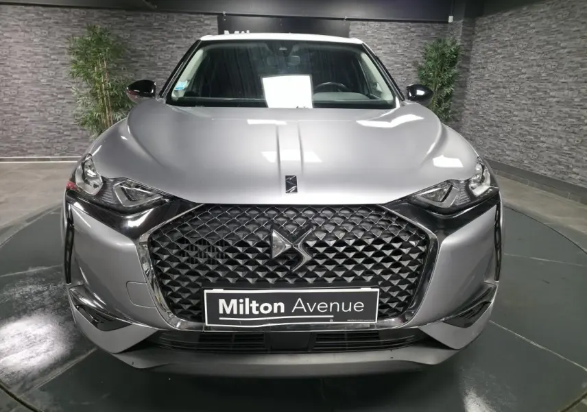 Vue frontale du DS3 Crossback gris métallisé avec calandre noire texturée et logo DS visible au centre.