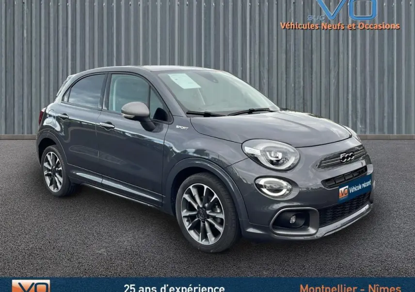 Vue 3/4 avant d'une FIAT 500X Sport gris métallisé avec jantes alliage 18 pouces sur fond urbain.