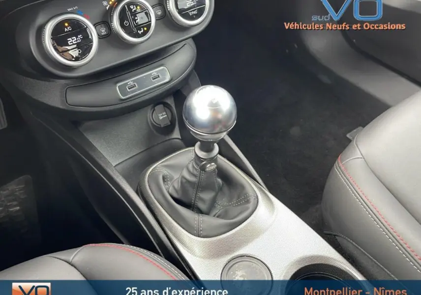 Gros plan sur la console centrale intérieure grise du Fiat 500X 2023 avec levier de vitesse manuel et commandes de climatisation.