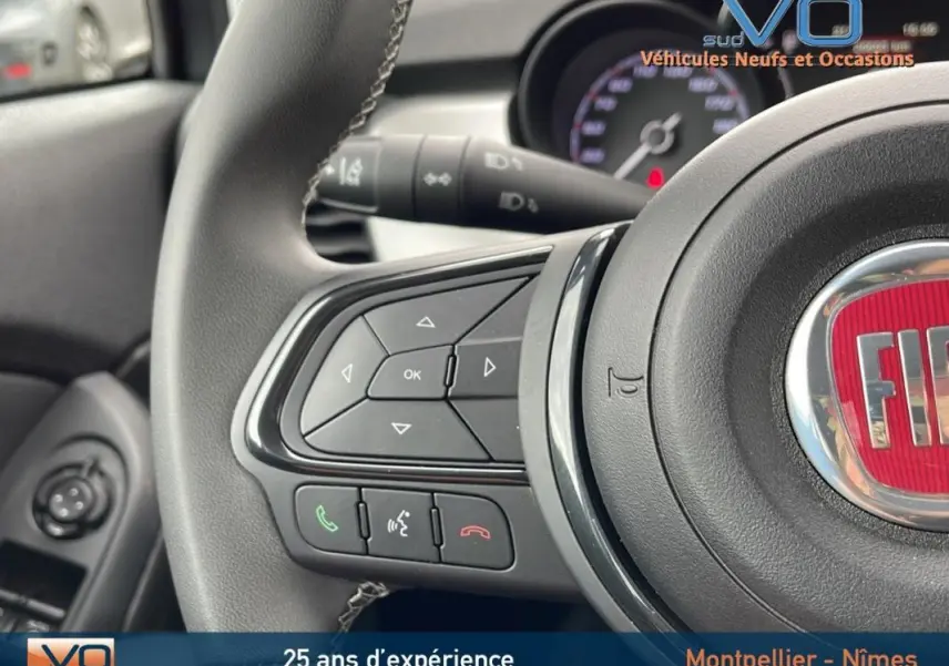 Gros plan sur le volant sport gris de la Fiat 500X 2023 avec commandes audio et téléphone intégrées.