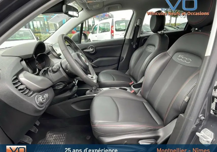 Intérieur de la FIAT 500X gris, vue côté conducteur montrant sièges sport en cuir noir avec surpiqûres rouges et volant sport.