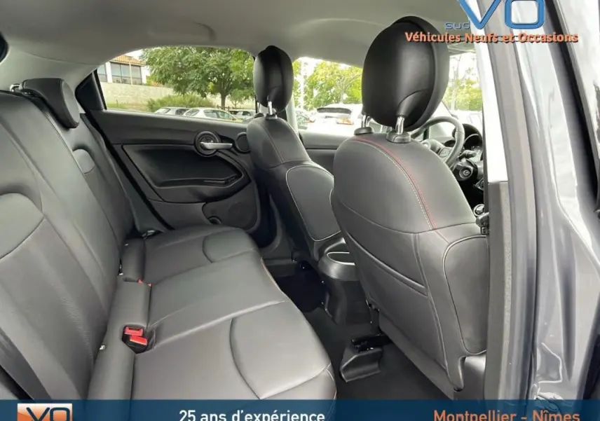 Intérieur arrière de la FIAT 500X gris, montrant les sièges en cuir noir et l'ouverture côté droit avec porte ouverte.