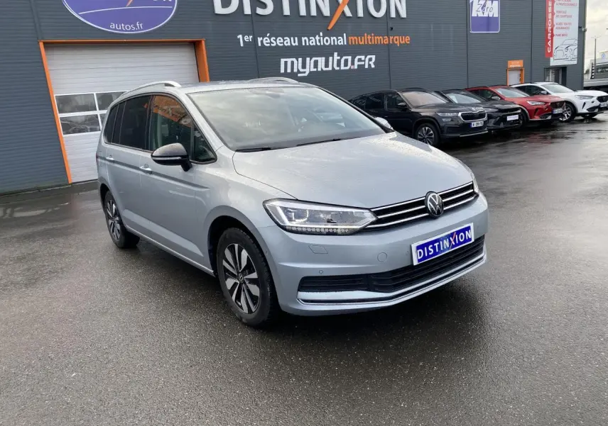 Volkswagen Touran 2025 Oyster Argent métallisé, vue 3/4 avant avec projecteurs IQ.Light et jantes distinctives.