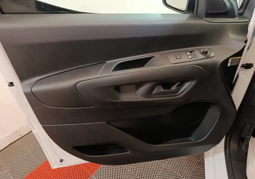 Vue intérieure côté gauche de la porte avant blanche du Peugeot Partner 2026 avec commandes électriques et poignée noire.