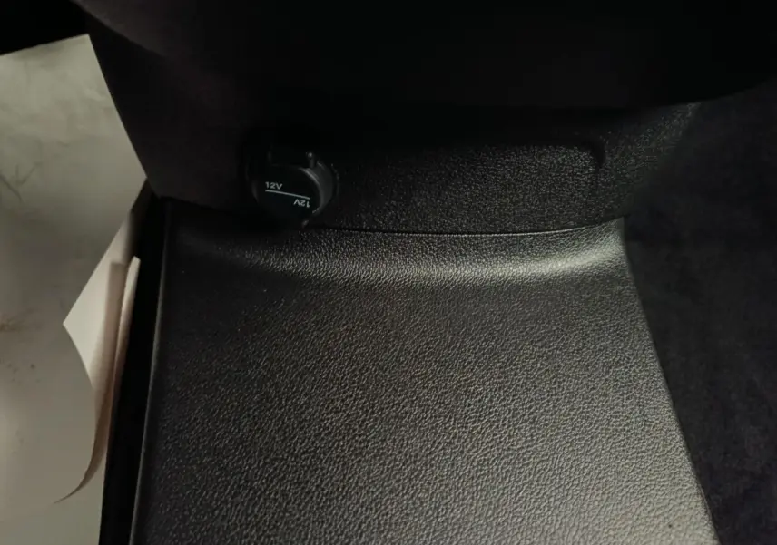 Prise 12V noire en gros plan sur la console centrale intérieure du Peugeot Partner blanc, version 2026.