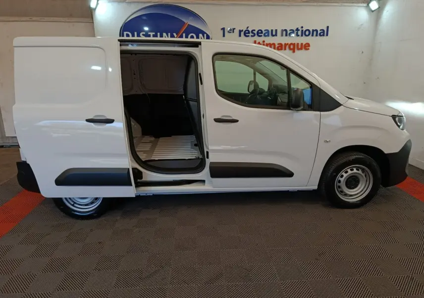 Vue de profil droit d’un Peugeot Partner blanc 2026 avec porte latérale coulissante ouverte, intérieur de chargement visible.