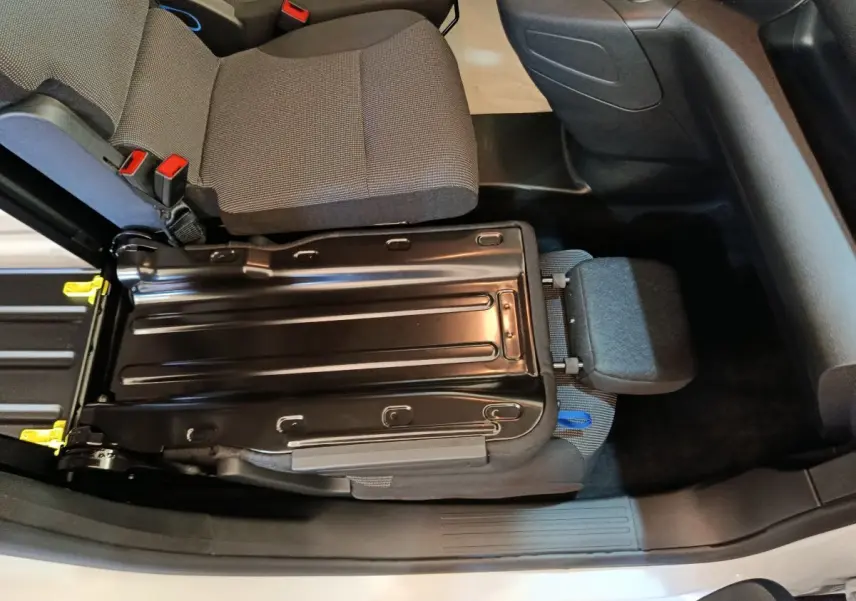 Vue intérieure plongeante du siège passager avant relevé du Peugeot Partner blanc, montrant la structure métallique et l'assise grise.